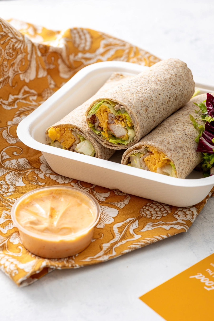 Tortillaba tekert Corn flakes bundás csirkecsíkok sült baconnel, cheddar sajttal, jégsalátával, paradicsommal majonézes szósszal